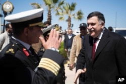 This image released by the media office of the unity government shows Fayez al-Sarraj, right, upon his arrival in Tripoli, Libya, March 30, 2016. He arrived by sea with six deputies to set up a temporary seat of power in a naval base.