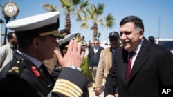 FILE - This image released by the media office of the unity government shows Fayez al-Sarraj, right, upon his arrival in Tripoli, Libya, March 30, 2016. He arrived by sea with six deputies to set up a temporary seat of power in a naval base.