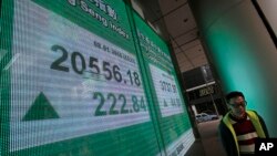 A man walks past an electronic board showing Hong Kong share index outside a local bank in Hong Kong, Jan. 8, 2016. 