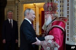 Patriark Gereja Ortodoks Rusia Kirill, kanan, menyapa Presiden Rusia Vladimir Putin setelah melakukan kebaktian Paskah Ortodoks di Katedral Kristus Juru Selamat, di Moskow, Rusia, Minggu, 16 April 2023. (Foto: via AP)