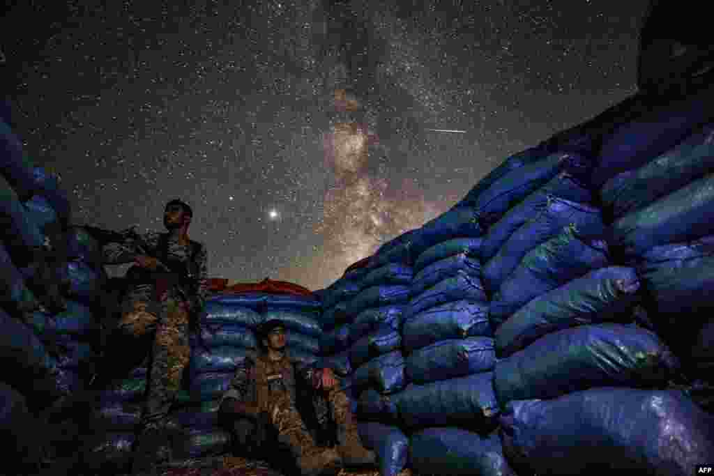 The Milky Way galaxy is seen in the sky above Syrian fighters of the Turkish-backed National Front for Liberation group while on watch duty in the town of Taftanaz along the frontlines in the rebel-held northwestern Idlib province.