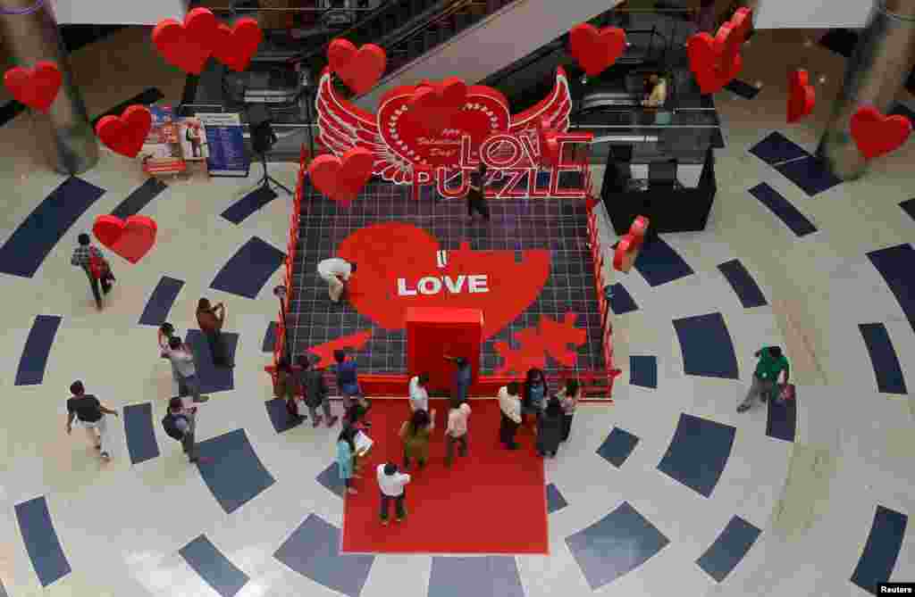 People arrange tiles of a heart-shaped puzzle during an event to promote Valentine's Day celebrations, inside a mall in Bengaluru, India, Feb. 12, 2018.