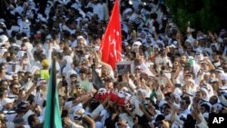 Thousands of Sunnis and Shi'ites from across Kuwait take part in a mass funeral procession for 27 people killed in a suicide bombing that targeted the Shi'ite Imam Sadiq Mosque a day earlier, at Kuwait's Grand Mosque in Kuwait city, June 27, 2015. 