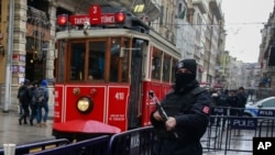A tram drives past a Turkish police officer as he patrols central Istanbul's Istiklal Avenue, the main shopping road of Istanbul, Jan. 5, 2017.