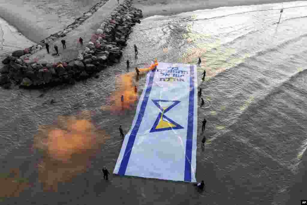 Relatives and supporters of Israelis held hostage by Hamas in Gaza mark 500 days of their captivity by spreading a massive Israeli flag depicting an hourglass in the Mediterranean Sea, in Tel Aviv.&nbsp;Hebrew of the flag reads &quot;Without the abductees, Israel runs out.&quot;