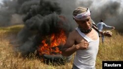 A Palestinian runs during clashes with Israeli troops, during a tent city protest along the Israel border with Gaza, demanding the right to return to their homeland, in the southern Gaza Strip, March 30, 2018.