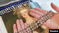 FILE - A staff member displays a pair of diamond bracelets, with approximately 140 to 150 carats and owned by Queen Marie Antoinette of France, in silver and yellow gold, circa 1776, during a preview at Christie's before their auction sale in Geneva, Nov. 3, 2021.