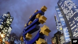 The Euro sculpture stands in front of the European Central Bank, right, in Frankfurt, Germany, December 16, 2011.