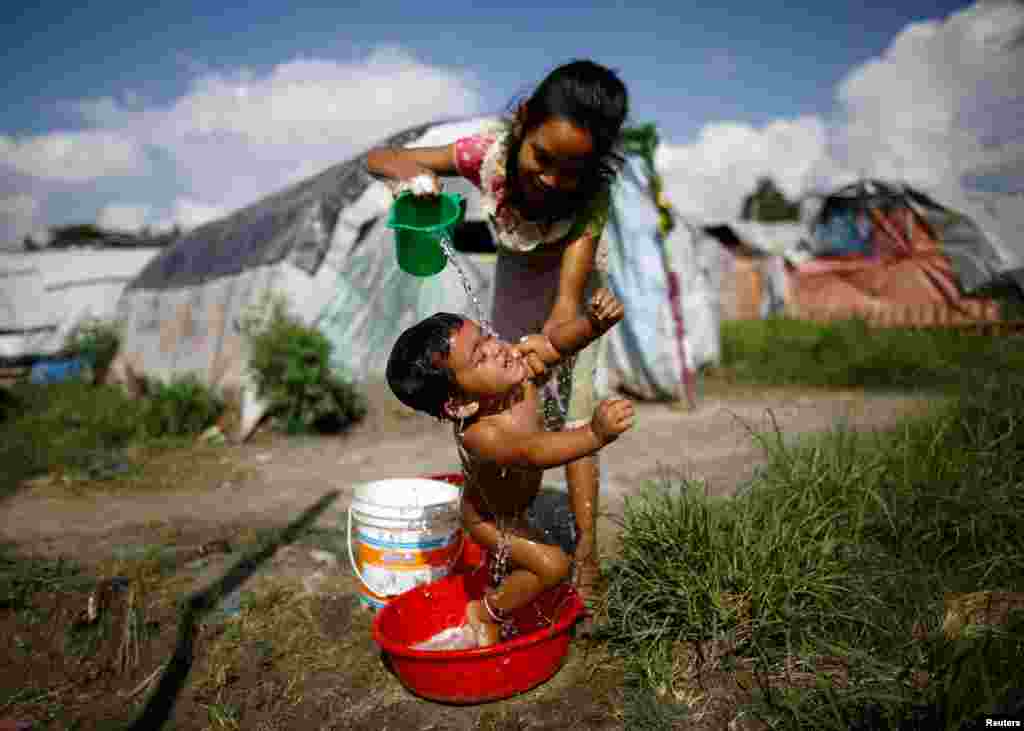 Seorang anak perempuan memandikan adiknya di kamp pengungsi gemp di Chuchepati, Kathmandu, Nepal.