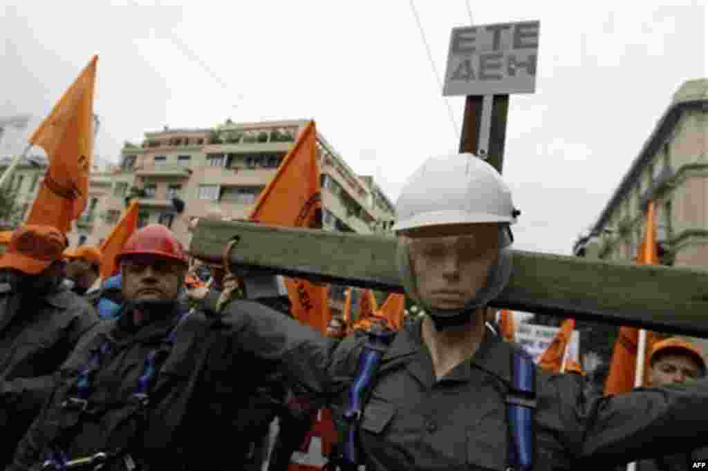 A unionist from the state electricity corporation PPC carries a cross with a sign whose initials read "here lies PPC crucified" during a protest in Athens, Wednesday, Dec. 15, 2010. Hundreds of protesters clashed with riot police across central Athens Wed