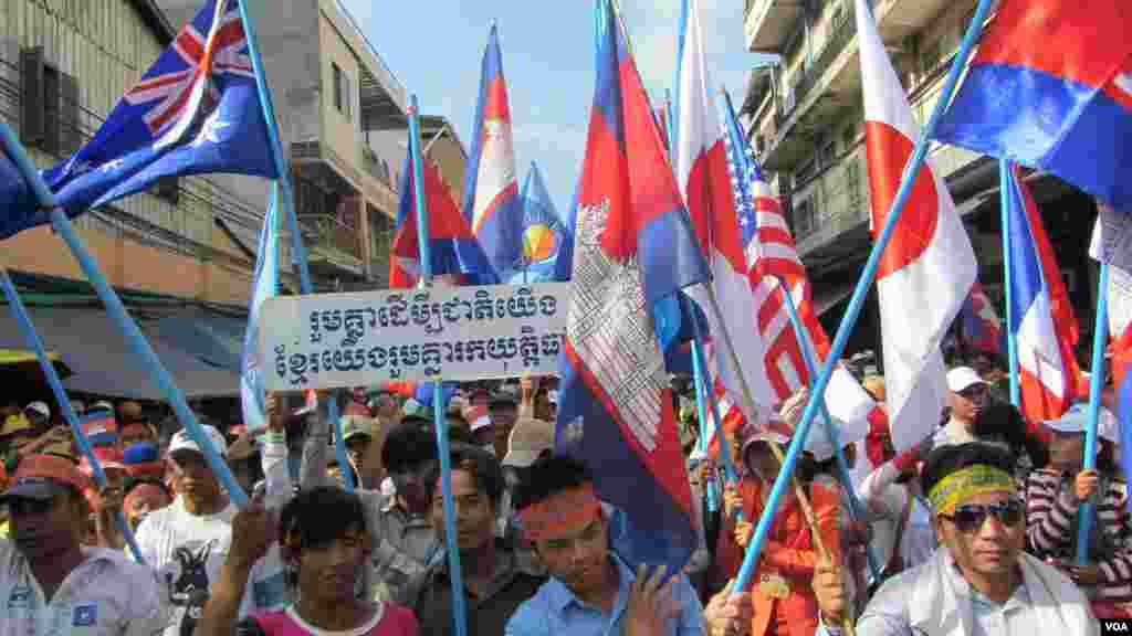 Young opposition supporters hold flags of major donor countries to Cambodia urging them to support their calls for an independent investigation into election irregularities, Phnom Penh, Oct. 23, 2013. (Khoun Theara/VOA Khmer)