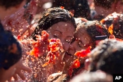 Two women taking a selfie get hit with tomatoes during a tomato fight in front of the Royal Palace turning Amsterdam's central Dam square into a red pulpy mess Sunday, Sept. 14, 2014.