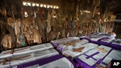 Des vêtements de certaines des personnes tuées durant le génocide du Rwanda pendent au-dessus de cercueils contenant les restes de plusieurs victimes dans un sanctuaire commémoratif à une église catholique à Ntarama, Rwanda, 4 Avril 2014.