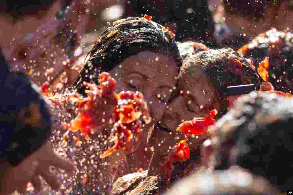 Two women taking a selfie get hit with tomatoes during a tomato fight in front of the Royal Palace turning Amsterdam&#39;s central Dam Square into a red pulpy mess, the Netherlands.