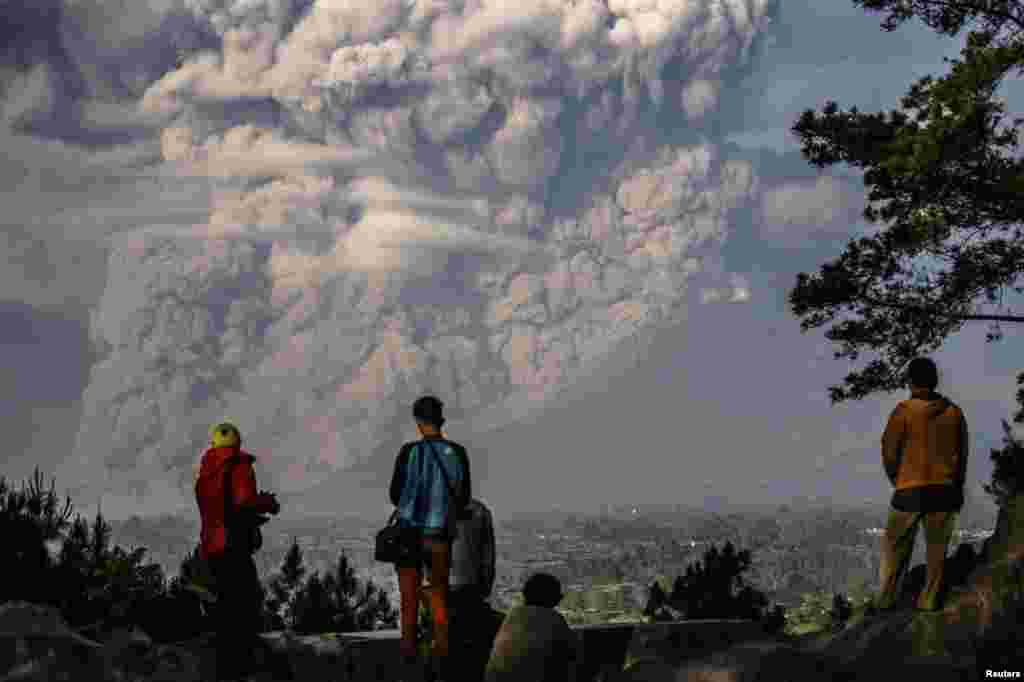 People watch as Mt. Sinabung ejects ash into the air during an eruption in Karo regency, Indonesia&#39;s North Sumatra province in this photo taken by Antara Foto.