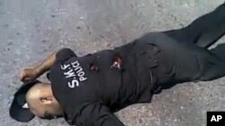 This undated amateur video image posted on the internet and shown on Syrian state television shows a Syrian policeman lying on the ground apparently dead from gunshot wounds in Jisr al-Shughour, northern Syria. (AP cannot independently verify the location