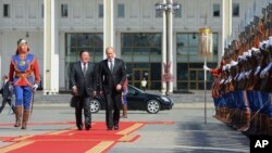 Russian President Vladimir Putin, right, and Mongolia's President Elbegdorj Tsakhia, center, review the guard of honor at Genghis Khan Square during a welcome ceremony in Ulan Bator, Mongolia, Sept. 3, 2014.