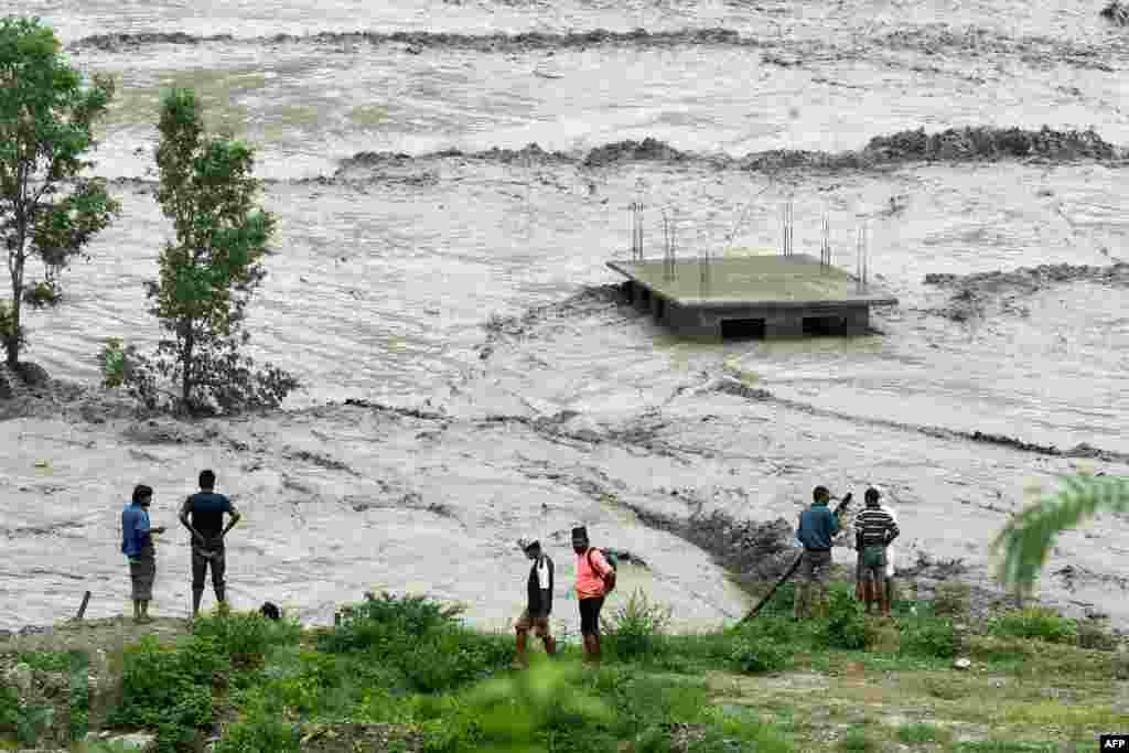 Residents stand along the banks of the overflowed Melamchi River following heavy monsoon rains in Sindhupalchok, some 70 kilometers northeast of Kathmandu, Nepal.