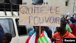 A man holds up a sign which reads, "leave the power," during an opposition protest calling for the immediate resignation of President Faure Gnassingbe in Lome, Togo, Sept. 7, 2017. 