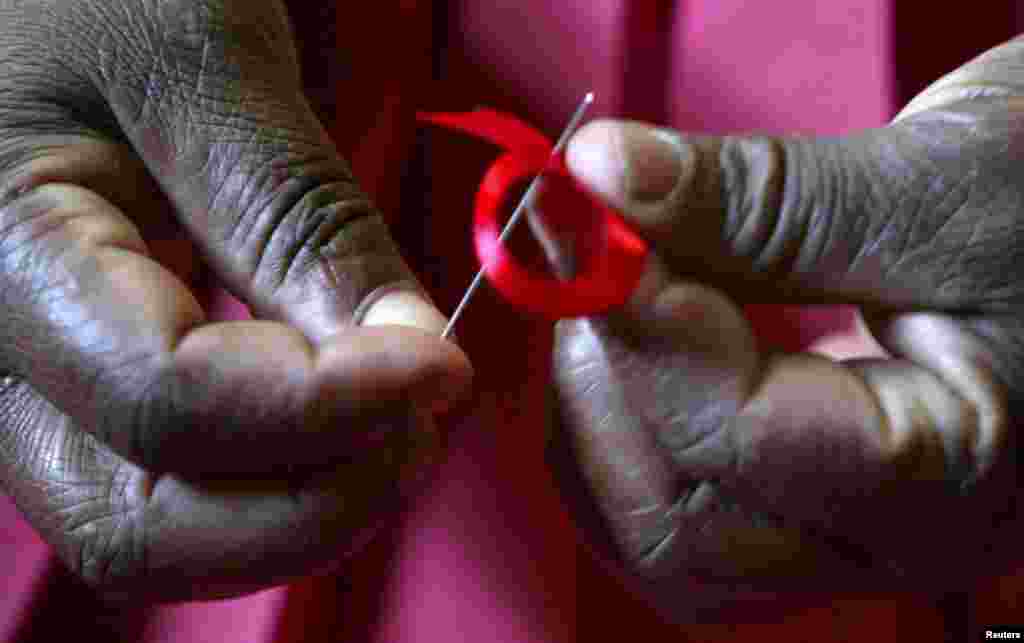 A Kenyan woman prepares ribbons ahead of World Aids Day at Beacon of Hope centre, a non-government organization formed to address women's problem of HIV/AIDS in Nairobi, November 25, 2004. Dramatic scientific advances since HIV was first discovered 30 yea