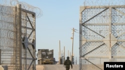 FILE - An Israeli soldier walks near a truck, as trucks carrying humanitarian aid make their way to the Gaza Strip, amid the ongoing conflict in Gaza between Israel and Hamas, at Erez Crossing in southern Israel, Oct. 21, 2024.