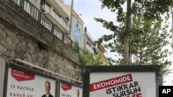 Pedestrians walk between election billboards as Dolmabahce Mosque is seen in the background in Istanbul, Turkey, on Friday, June 10, 2011