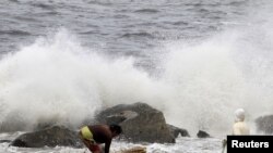 Residents collect recyclable materials from floating garbage found in the sea, while big waves crash along the coastline due to strong winds brought by Typhoon Goni, locally named as Ineng, at Manila bay, Aug. 22, 2015. 