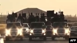 FILE - An image grab taken from a video released by Islamic State group's official Al-Raqqa site via YouTube allegedly shows Islamic State (IS) group recruits riding in armed trucks in an unknown location. 