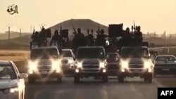 FILE - An image grab taken from a video released by Islamic State group's official Al-Raqqa site via YouTube allegedly shows Islamic State (IS) group recruits riding in armed trucks in an unknown location.