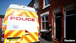 FILE - A police officer stand outside a property in Moss Side, following overnight raids in Manchester, Britain, May 25, 2017. 