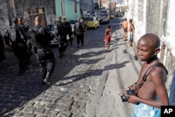 A boy looks at police officers on patrol in the Morro da Providencia slum in Rio de Janeiro, April 26, 2010.