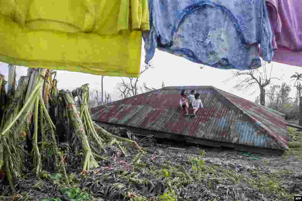 필리핀 마닐라 북서부 카시구란 마을에서 최근 태풍 피해로 부서진 집 지붕 위에 아이들이 앉아있다.