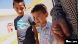 Salvadoran migrant Epigmenio Centeno and his sons, nine-year old Axel Jaret (L) and three-year old Steven Atonay, pose for a photograph outside the shelter House of the Migrant, after Epigmenio decided to stay with his children in Mexico due to U.S. Presi