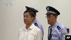 In this image taken from video, disgraced politician Bo Xilai, center, enters the courtroom, flanked by police guards at Jinan Intermediate People's Court in eastern China's Shandong province, Aug. 22, 2013. 