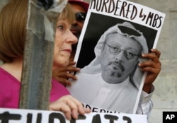 FILE - In this Oct. 10, 2018, file photo, people hold signs during a protest at the Embassy of Saudi Arabia about the disappearance of Saudi journalist Jamal Khashoggi, in Washington.