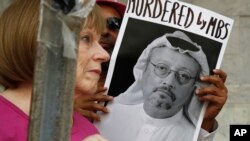 FILE - People hold signs during a protest at the Embassy of Saudi Arabia about the disappearance of Saudi journalist Jamal Khashoggi, in Washington,Oct. 10, 2018. 