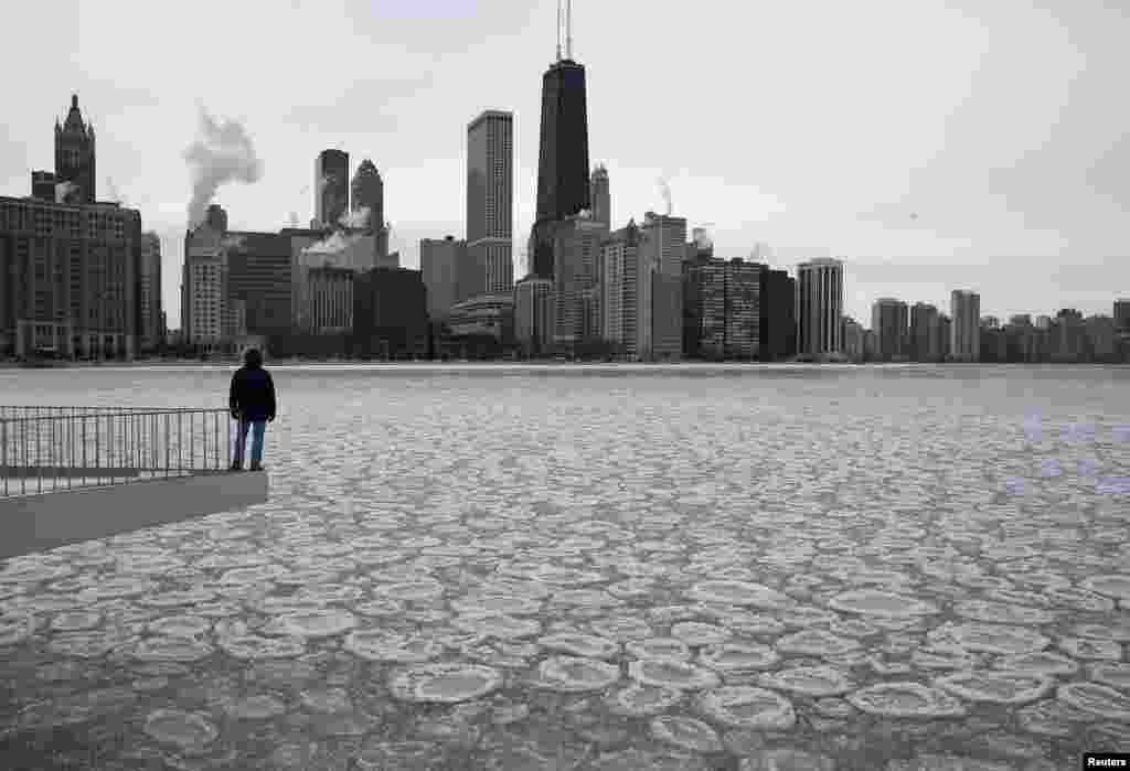 Seorang pria menikmati suasana di Danau Michigan yang membeku dengan latar belakang kota Chicago.