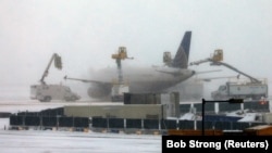 Pesawat United Airlines sedang dibersihkan dari es setelah badai salju mengakibatkan 460 penerbangan dibatalkan di Bandara International Denver, Colorado, 26 November 2019. 