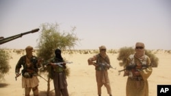 Fighters from Islamist group Ansar Dine stand guard during a hostage handover, in the desert outside Timbuktu, Mali, April 24, 2012.