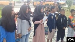 Aksi solidaritas terhadap Surabaya oleh puluhan remaja lintas agama di taman kota Tentena, Kabupaten Poso, Sulawesi Tengah, Senin malam 14/5. (VOA/Yoanes)