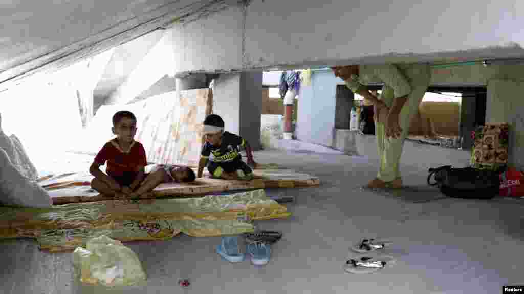 Iraqi Christian children, who fled the violence in the village of Qaraqosh, sit on a mattress at their makeshift shelter in an abandoned building in Irbil, north of Baghdad, Aug. 11, 2014. 