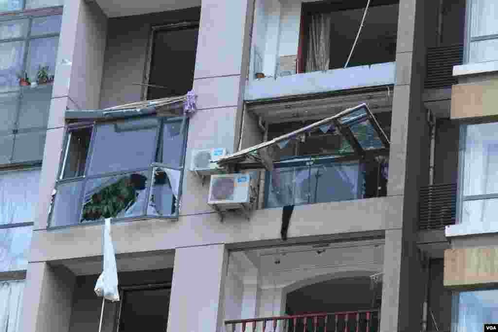 天津爆炸事故现场，核心爆炸区周围多座居民楼窗户被震碎，高速公路桥梁受损，多辆大货车被炸翻，小汽车起火或被砸，多名当地居民仍逗留在事故现场。（美国之音记者东方拍摄）