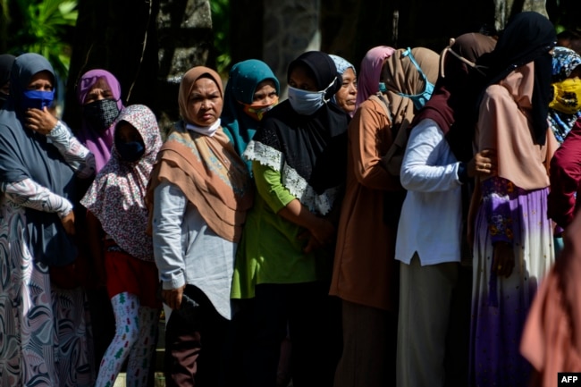 Sejumlah perempuan menggunakan masker wajah antre membeli sembako murah di Banda Aceh, 14 Mei 2020. (Foto: AFP)