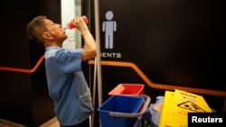 Petugas pembersih berusia 80 tahun, Lim Chin Seng, beristirahat dari pekerjaannya di sebuah pusat perbelanjaan Singapura. (Reuters/Edgar Su)