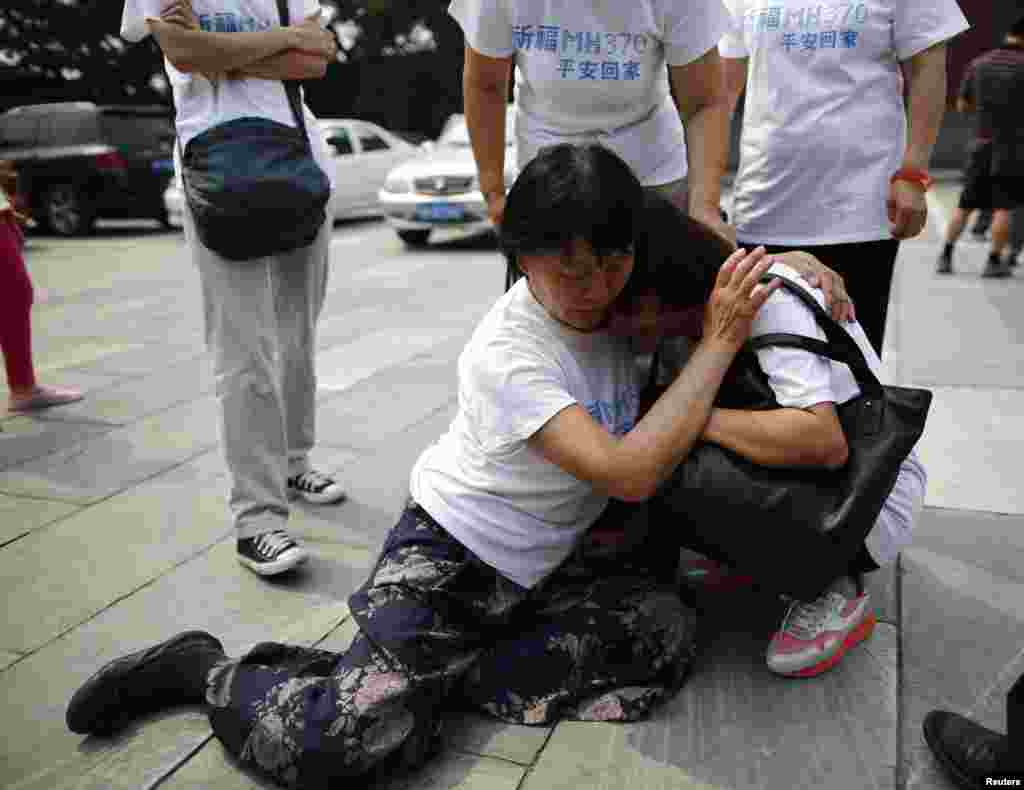 A family member of a passenger aboard the missing Malaysia Airlines flight MH370 comforts another relative as they gather to pray at Yonghegong Lama Temple in Beijing, China.