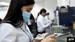 FILE PHOTO - An ACLEDA Bank employee counts US currency inside the bank in Phnom Penh on May 25, 2020. (Photo by TANG CHHIN Sothy / AFP)