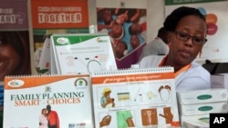 FILE - Health worker Sylvia Marettah Katende displays reproductive health products and information at a family planning exhibition in Kampala, Uganda, Sept. 26, 2017. Like Uganda, neighboring Kenya is now starting to promote vasectomies in family planning.