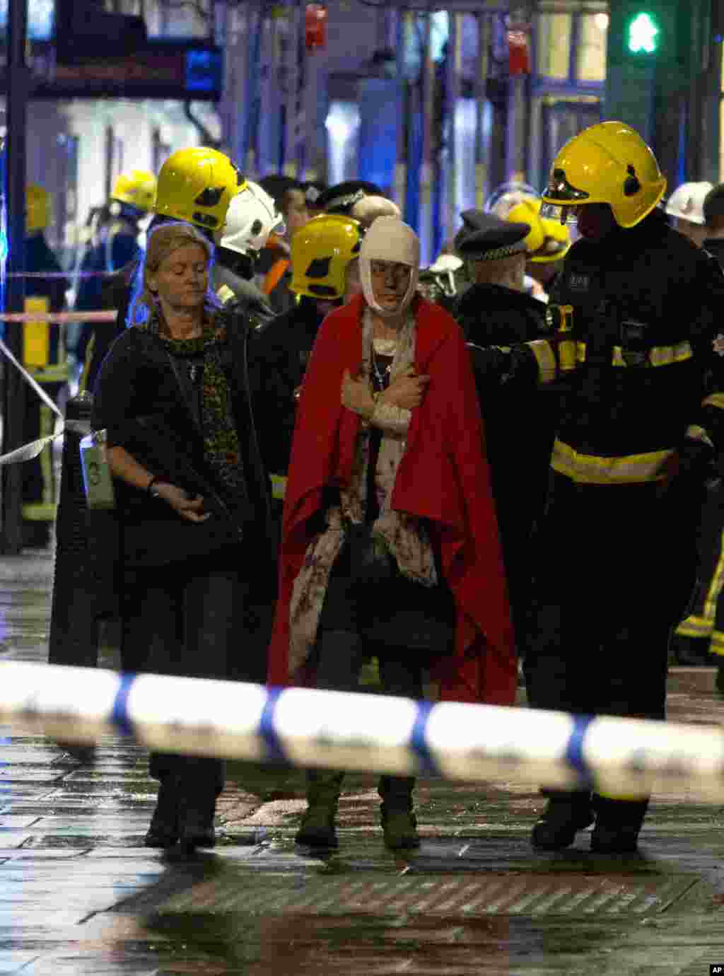 A woman walks, bandaged and wearing a blanket given by emergency services, following the partial collapse of the ceiling at the Apollo Theatre during a performance at the height of the Christmas season, Shaftesbury Avenue, central London, Dec. 19, 2013.
