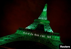 FILE - The Eiffel tower is illuminated in green with the words "Paris Agreement is Done," to celebrate the Paris U.N. Climate Change agreement in Paris, France, Nov. 4, 2016.