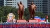 Les gens portent des drapeaux devant les statues du fondateur de la Corée du Nord, Kim Il Sung, à gauche, et le défunt leader Kim Jong Il lors d'un défilé militaire marquant le 70e anniversaire de la fondation de la Corée du Nord à Pyongyang, en Corée du Nord, le 9 septembre 2018.